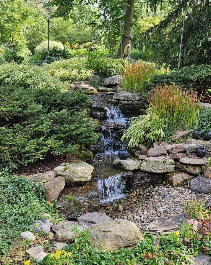 Backyard landscape design with natural stone waterfall and garden plants in Cuyahoga County Ohio