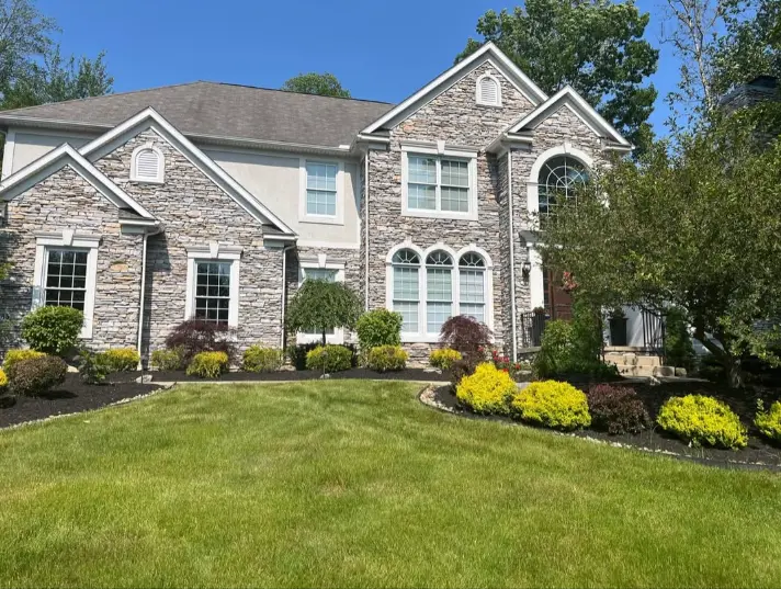 Established landscape bed with colorful shrubs at a Northeast Ohio stone home
