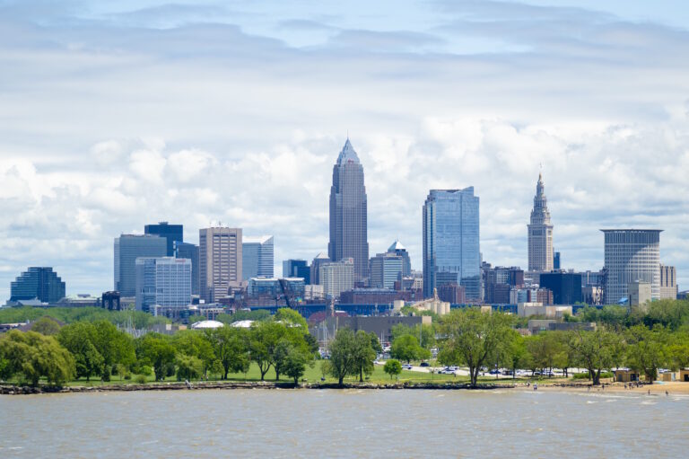 Downtown Cleveland skyline with Terminal Tower and Key Tower viewed over green treetops from Edgewater Park